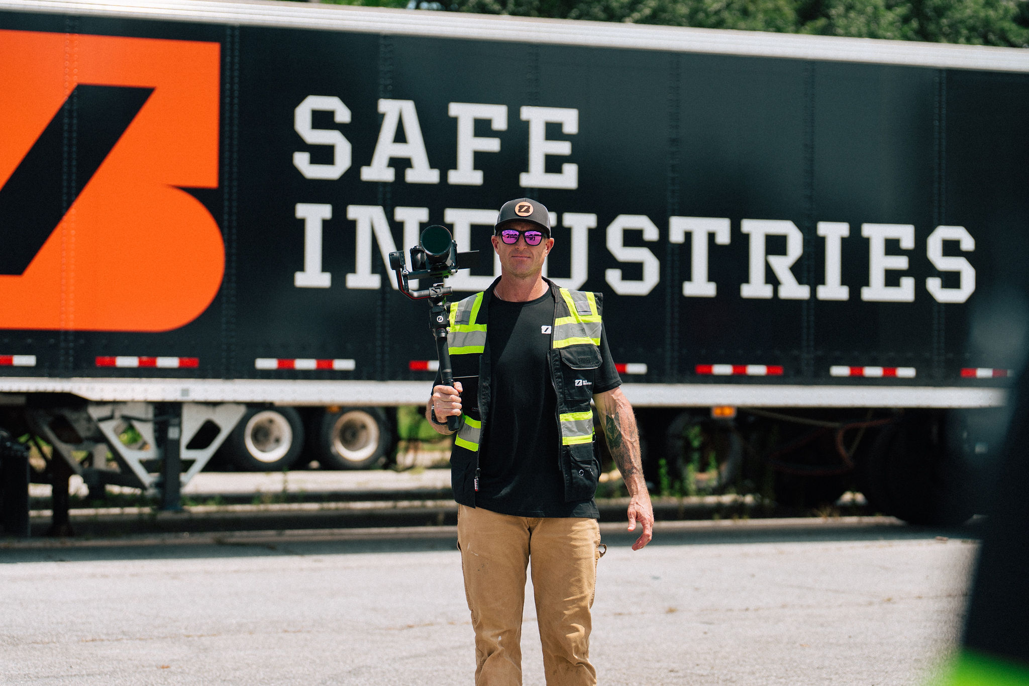 A Safe Industries content operator standing in front of a branded semi trailer, camera in hand